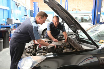 Two mechanics working under the hood of a car