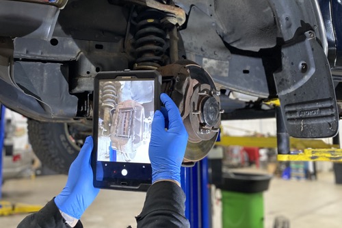 Brake repair and service at Collinsville Auto. A technician takes a picture of worn brake pads as part of a digital vehicle inspection before recommending replacement of brakes.