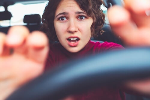 When to Come in for a Brake Inspection and Repairs at Collinsville Auto Repair in Canton, Ct. image of a young woman scared bracing her hands on the steering wheel