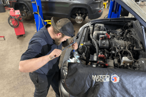 Engine Repair in Canton, CT | Collinsville Auto Repair. Image of Collinsville’s auto mechanic working on a car engine in a car garage.