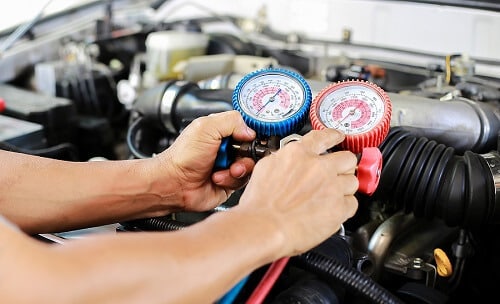 A/C Repair & Services in Canton, CT | Collinsville Auto Repair. Closeup image of an auto mechanic checking a car’s aircon condition with a meter gauge.