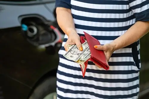 Improve Your Gas Mileage with BG Engine Performance Restoration | Collinsville Auto Repair in Canton, CT. Closeup image of a woman’s hand counting money while standing at an open fuel tank. Concept image of rising fuel prices.