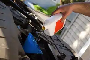 A mechanic pours motor oil into the engine at the end of an oil change.