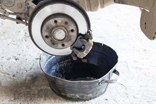 Collinsville Auto | old brake fluid is drained into steel basin in car workshop