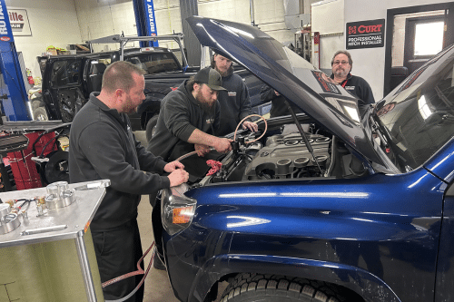 Collinsville Auto Repair performing BG Coolant Flush service in Canton, CT. Mechanics servicing a blue car inside the repair shop.