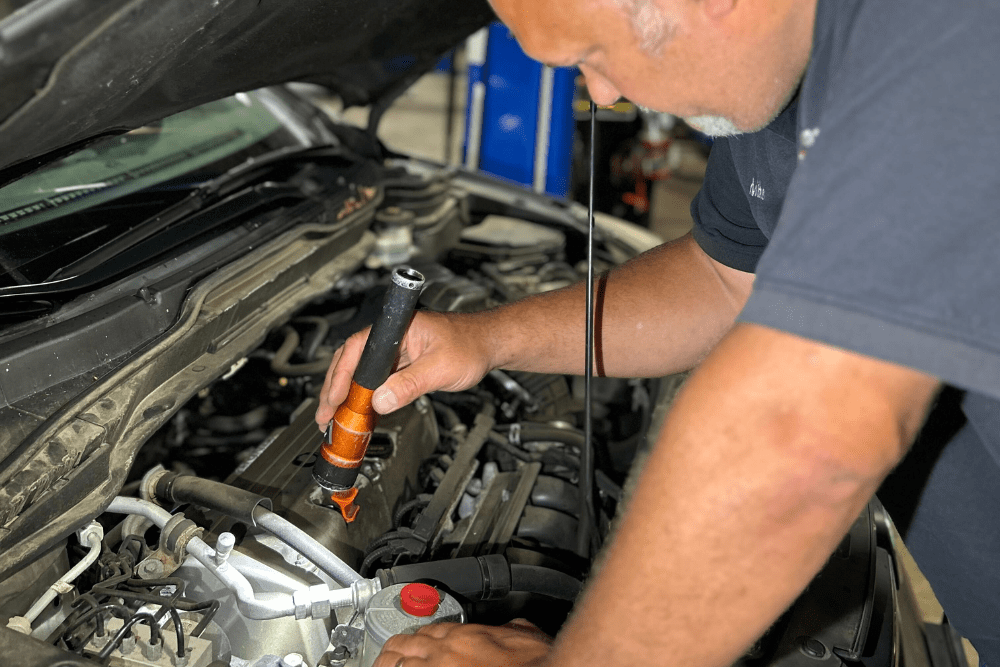 diy car repair, auto repair in Canton, CT at Collinsville Auto Repair. Image of a technician checking oil levels under the hood.