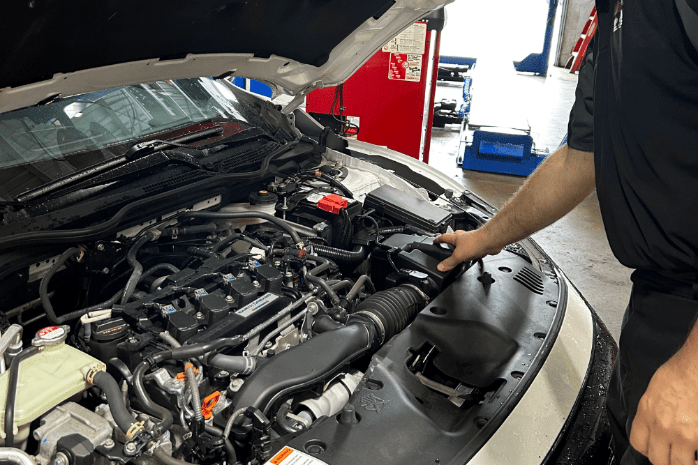 Car maintenance, auto repair in Collinsville, CT by Collinsville Auto Repair. Image of a technician inspecting under the hood of a vehicle, emphasizing accurate troubleshooting to maintain safety and performance.