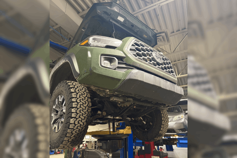 Car maintenance, auto repair in Canton, CT by Collinsville Auto Repair. Image of a Toyota Tacoma lifted in a professional repair shop with the hood open during inspection, highlighting expert diagnostics, undercarriage inspection, and routine maintenance to keep trucks running reliably.
